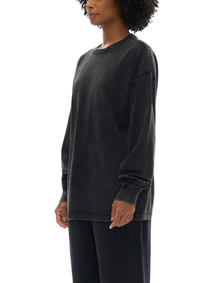 Woman wearing a loose, faded black long-sleeve crewneck shirt and black pants on white background